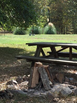 A picnic table in a park with a stack of firewood in front. - Spacious Cabin on 18 beautiful acres 20min from downtown. Spa services available (Pearcy)