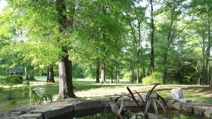 A serene outdoor area with a pond, stone bridge, and a sculpture.