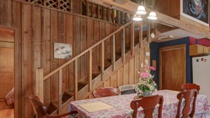 A wooden interior with a dining table set for four, a staircase, and a kitchen area.