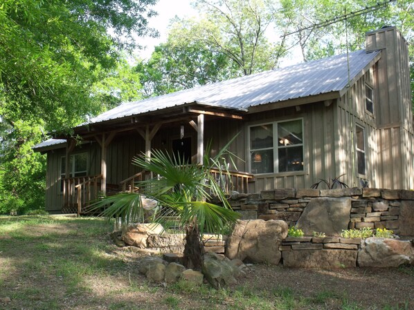 A rustic cabin with a porch, stone foundation, and a large window. - Spacious Cabin on 18 beautiful acres 20min from downtown. Spa services available (Pearcy)
