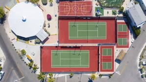 An aerial view of a sports complex with multiple tennis courts, a basketball court, and a large circular structure. - Enjoy Caribbean weather in the USA. Openings August 2026 forward!  (Cudjoe Key)