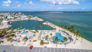 A coastal resort with multiple swimming pools, a beach area, and a parking lot. - Enjoy Caribbean weather in the USA. Openings August 2026 forward!  (Cudjoe Key)