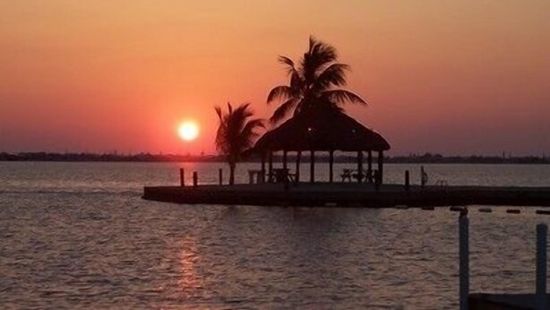 A sunset over a body of water with a structure that appears to be a gazebo or pavilion. - Enjoy Caribbean weather in the USA. Openings August 2026 forward!  (Cudjoe Key)