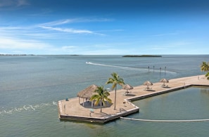 Ein tropisches Strandresort mit Pool, Palmen und einem Boot im Wasser.