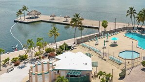 A resort with a pool, lounge chairs, palm trees, and a view of the water. - Enjoy Caribbean weather in the USA. Openings August 2026 forward!  (Cudjoe Key)
