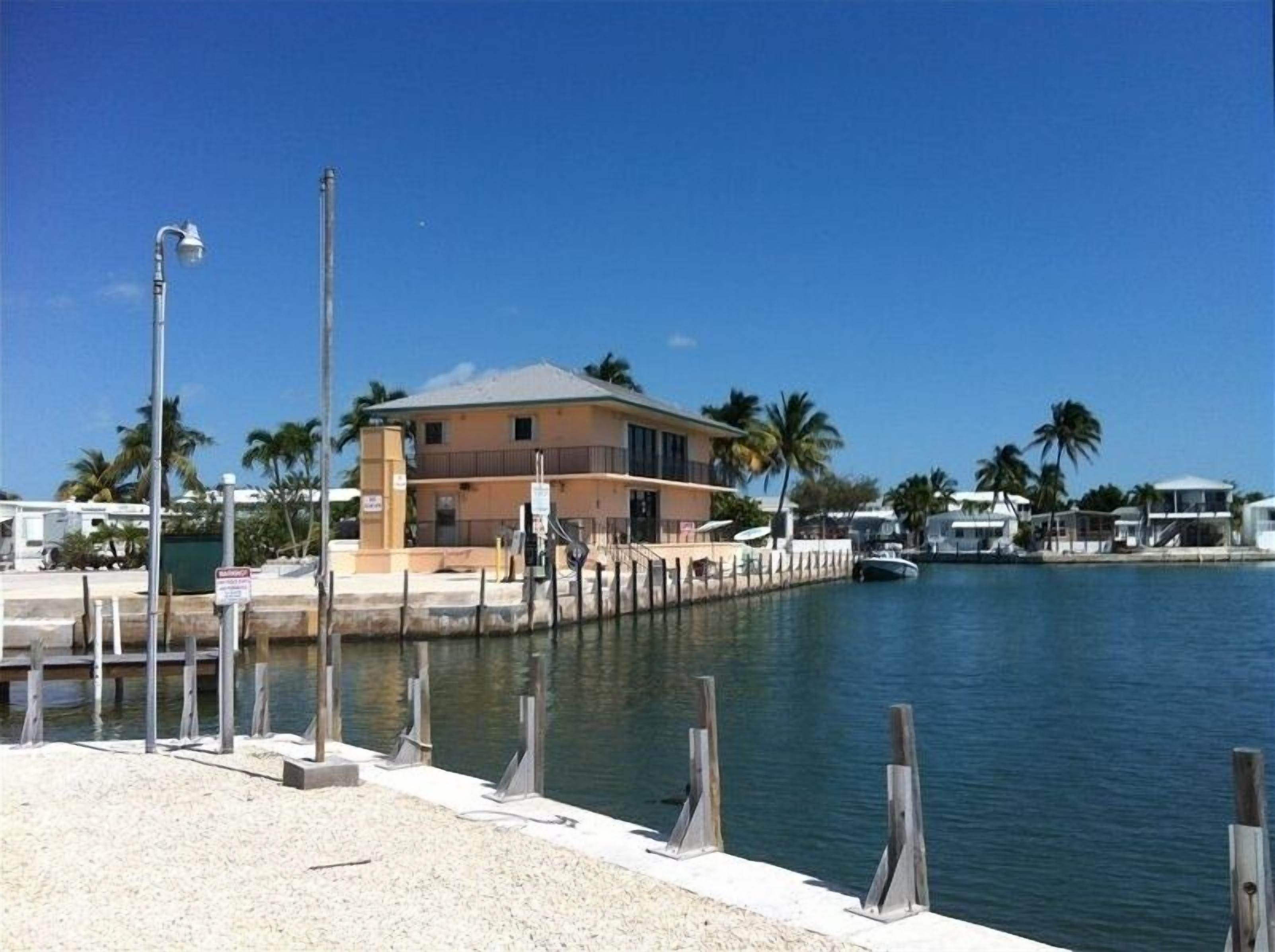 A waterfront property with a two-story building, a dock, and palm trees.