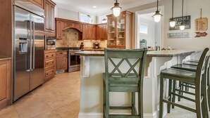 Una cocina moderna con armarios de madera, electrodomésticos de acero inoxidable e iluminación colgante.