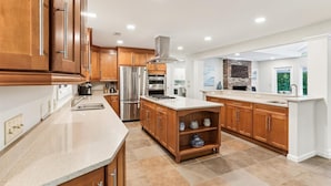 Une cuisine moderne avec des meubles en bois, des appareils en acier inoxydable et un grand îlot central.