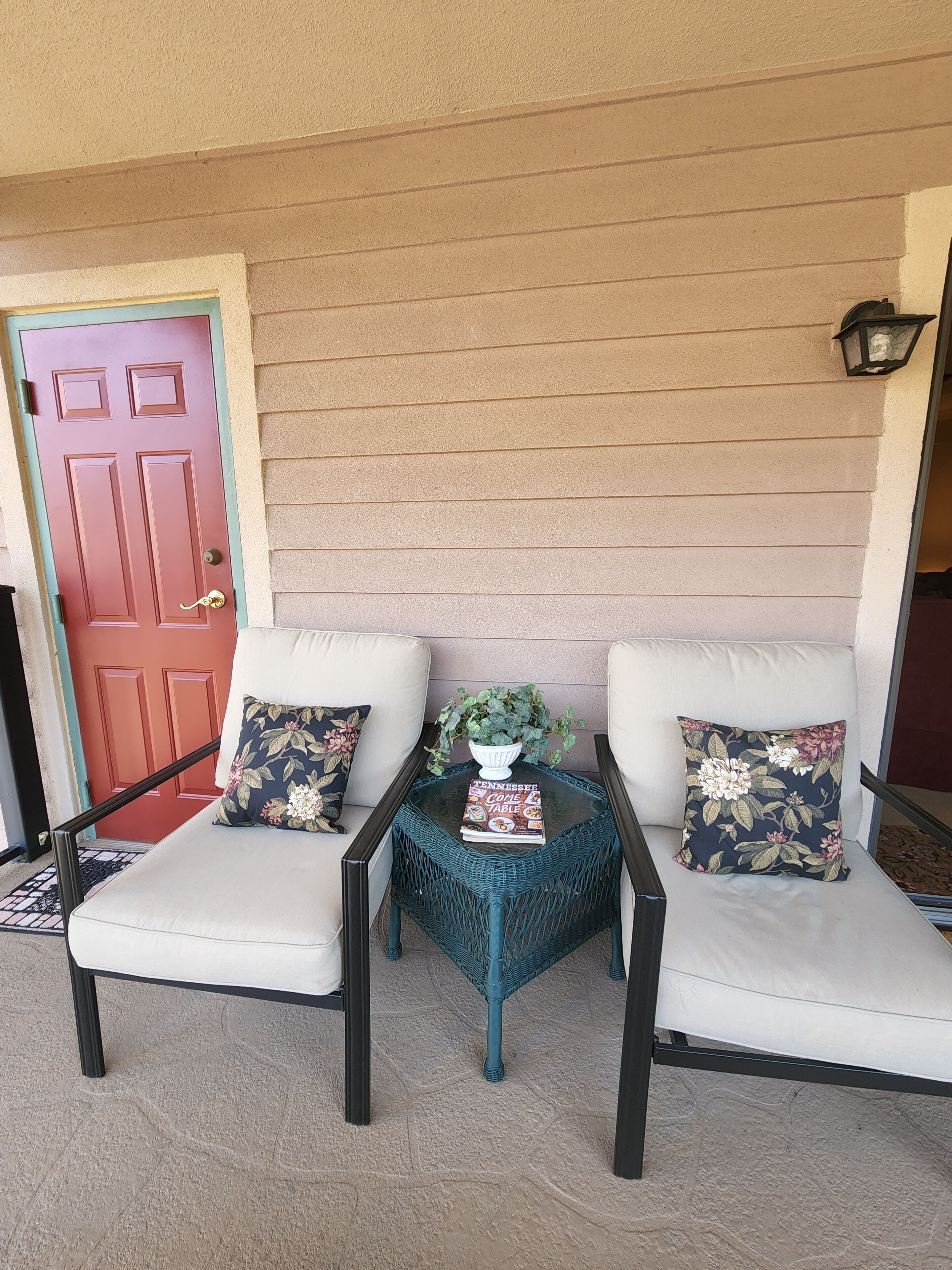 A seating area with two white cushioned chairs, a small table with a book, and a potted plant.