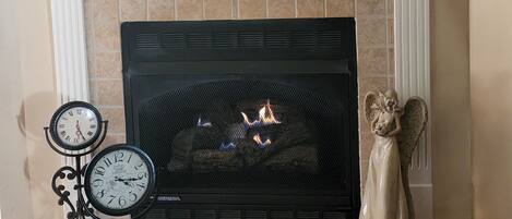 Una chimenea con repisa, un reloj y una estatua decorativa de un ángel.