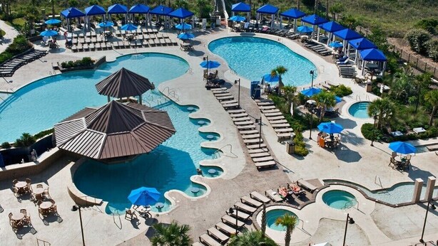 Et resort med flere swimmingpools, liggestole og parasoller.