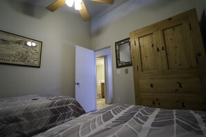 A bedroom with two beds, a wooden wardrobe, a map on the wall, and a door leading to another room. - Mt. CB - Great views, Great Space! Easy access to lifts! (Crested Butte)