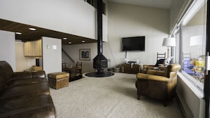 Ein Wohnzimmer mit Kamin, Ledersofas, einem Fernseher und einem Fenster mit Blick.