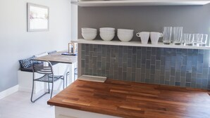A kitchen with a wooden countertop, a tiled backsplash, and shelves holding white dishes and glasses. - Peaceful, Sonoma oasis - heated pool, fire pit, outdoor dining - close to Plaza (Sonoma)