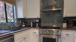 A modern kitchen with white cabinets, a stainless steel stove, and a coffee maker. - Peaceful, Sonoma oasis - heated pool, fire pit, outdoor dining - close to Plaza (Sonoma)