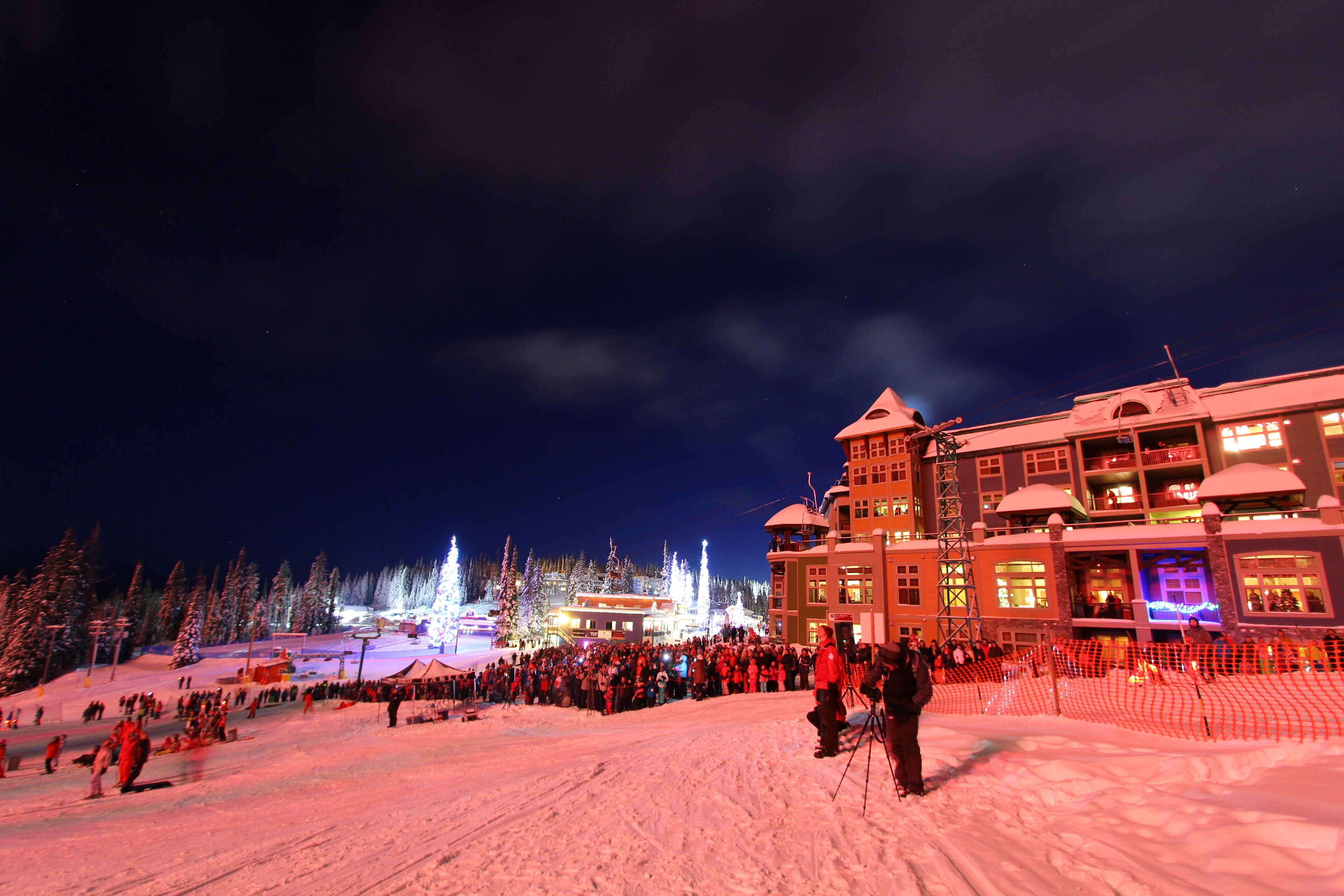 Un grand hôtel à plusieurs étages, avec une station de ski en arrière-plan.