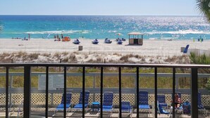 Une plage avec vue sur une piscine, comprenant des chaises longues et un poste de surveillance pour les sauveteurs.