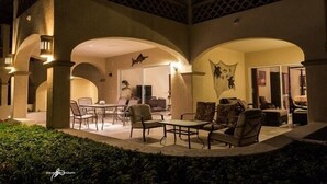 An outdoor patio area with a dining set and seating, enclosed by arches and columns, and a view into the interior. - Las Mananitas-Awesome Luxury Beachside Condo in Cabo! (san jose del cabo)