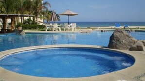 A pool area with lounge chairs and umbrellas, a hot tub, and a view of the ocean. - Las Mananitas-Awesome Luxury Beachside Condo in Cabo! (san jose del cabo)