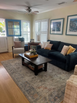 A living room with a dark blue sofa, a wooden coffee table, a patterned rug, and a ceiling fan. - Cozy Slice Of Paradise Just Steps From The Beach!! (Newport Beach)