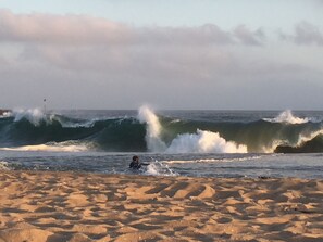 Una spiaggia con onde alte e una persona che fa surf.