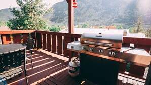 Un barbecue installé sur une terrasse en bois, avec une vue sur les montagnes en arrière-plan.