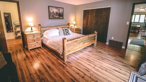 Une chambre à coucher avec un lit en bois, deux tables de chevet avec des lampes, une grande armoire et un tableau au mur.