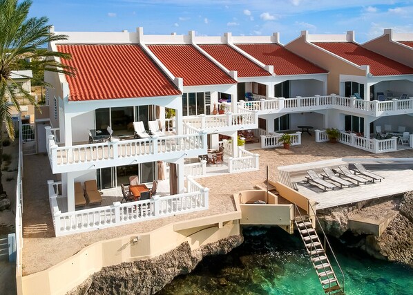 A multi-story hotel with balconies, outdoor seating, and a pool area.