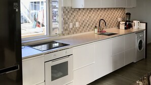 Eine moderne Küche mit Einbauofen, Waschmaschine und Fenster mit Ausblick.