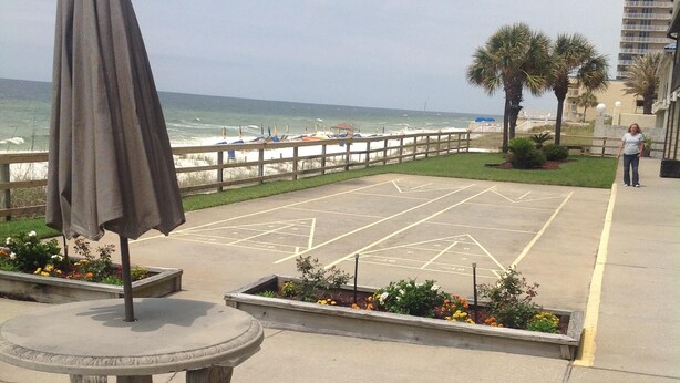 A beachfront patio with a table and benches, a wooden fence, and a view of the ocean. - Check out new rates for summer (Panama City Beach)