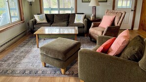 Una sala de estar acogedora con sofá, sillón, reposapiés y mesa de centro.