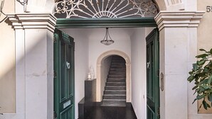 A building entrance with a staircase leading inside, a green door, and a decorative archway.