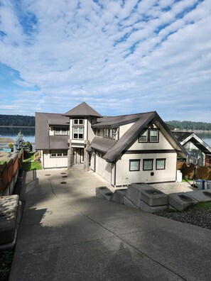 Une maison à deux étages avec un garage, une allée et une vue sur un lac.