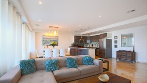 Een moderne woonkamer met een beige hoekbank, een houten salontafel en een keuken op de achtergrond.