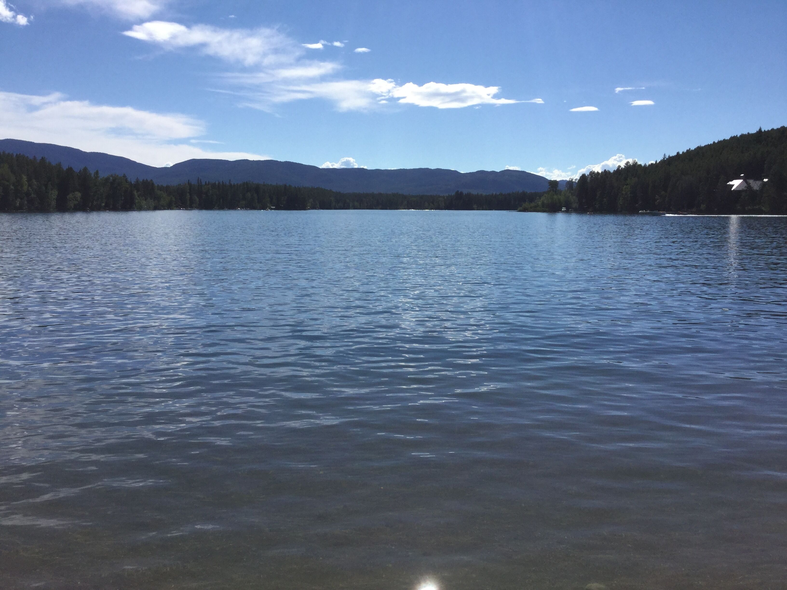 Un lac paisible, avec des montagnes en arrière-plan et un ciel dégagé.