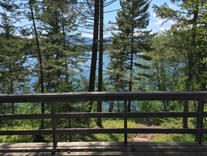 A wooden deck with a view of a forest and a lake.