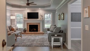 A living room with a fireplace, a television, and a ceiling fan. - Renovated Home in Downtown Historic Franklin Close To Everything! (Franklin)