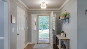 A hallway with white doors, a wooden console table with a small plant, and a hanging metal shelf. - Renovated Home in Downtown Historic Franklin Close To Everything! (Franklin)