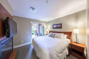 Una habitación de hotel con cama, televisión, escritorio y silla.