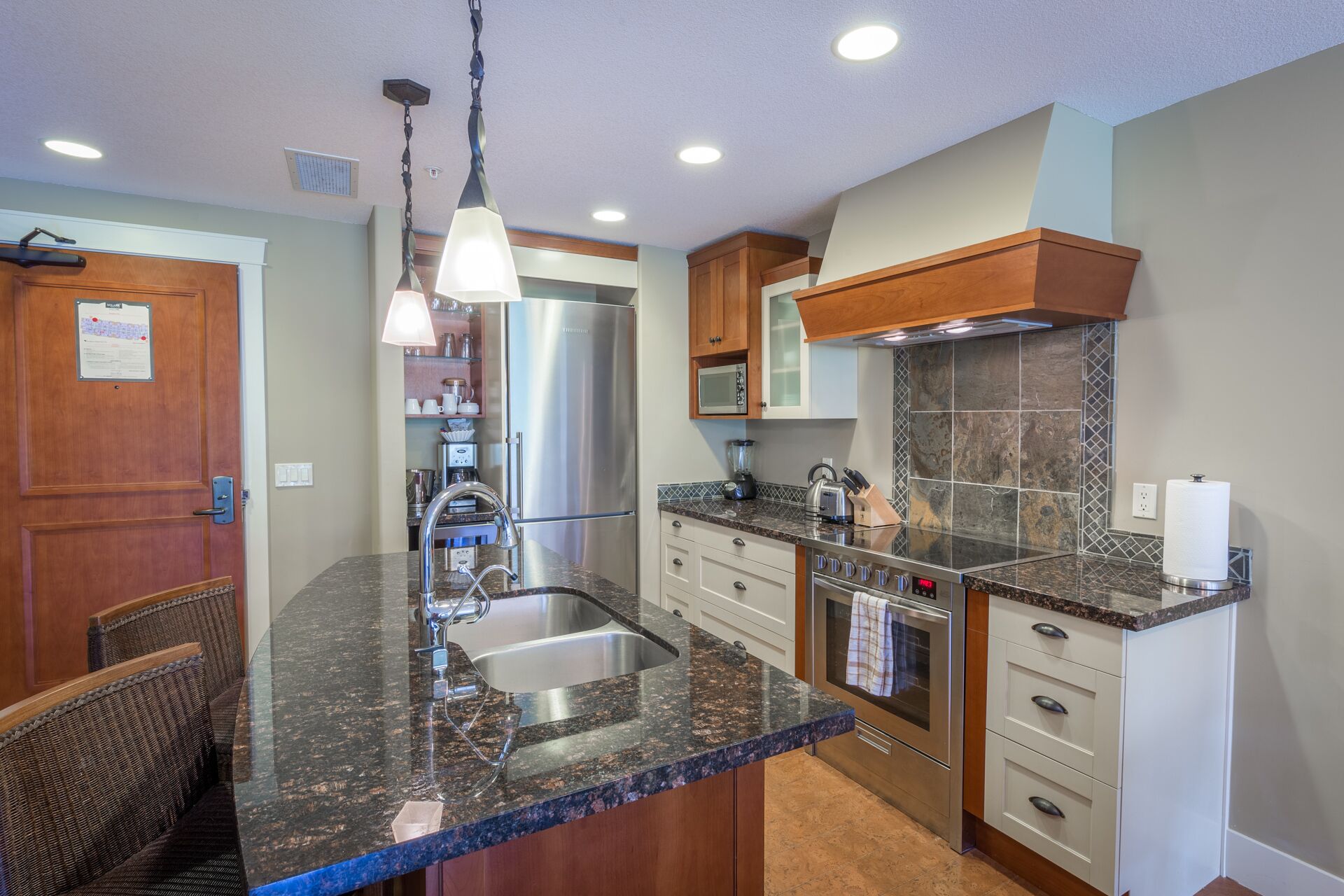 A modern kitchen with granite countertops, stainless steel appliances, and wooden cabinetry.