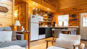 A cozy cabin-style room with a kitchenette, a dining area, and a living space with a sofa and chairs. - Secluded, Furnished, Log Home, Close To Many Adirondack Attractions. (Jay)