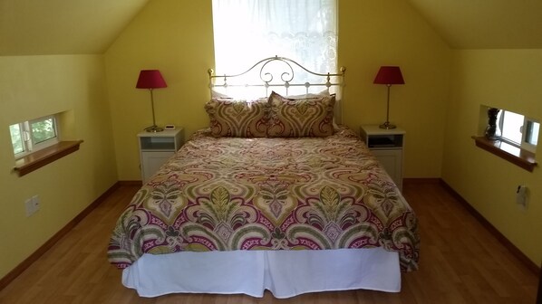 Un dormitorio con una cama, dos mesitas de noche, una ventana y una estantería.