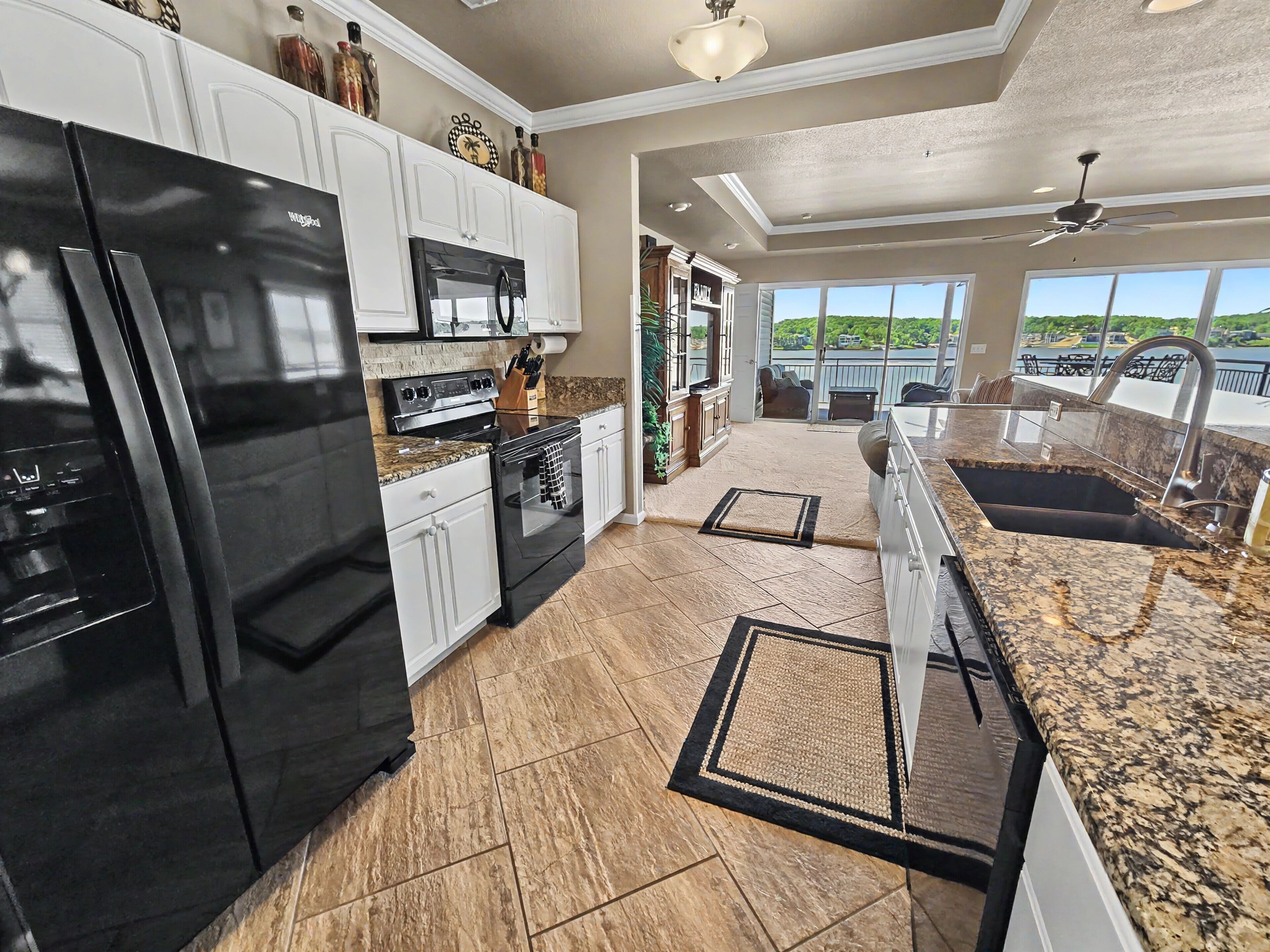 A kitchen with a refrigerator, stove, microwave, and granite countertops.