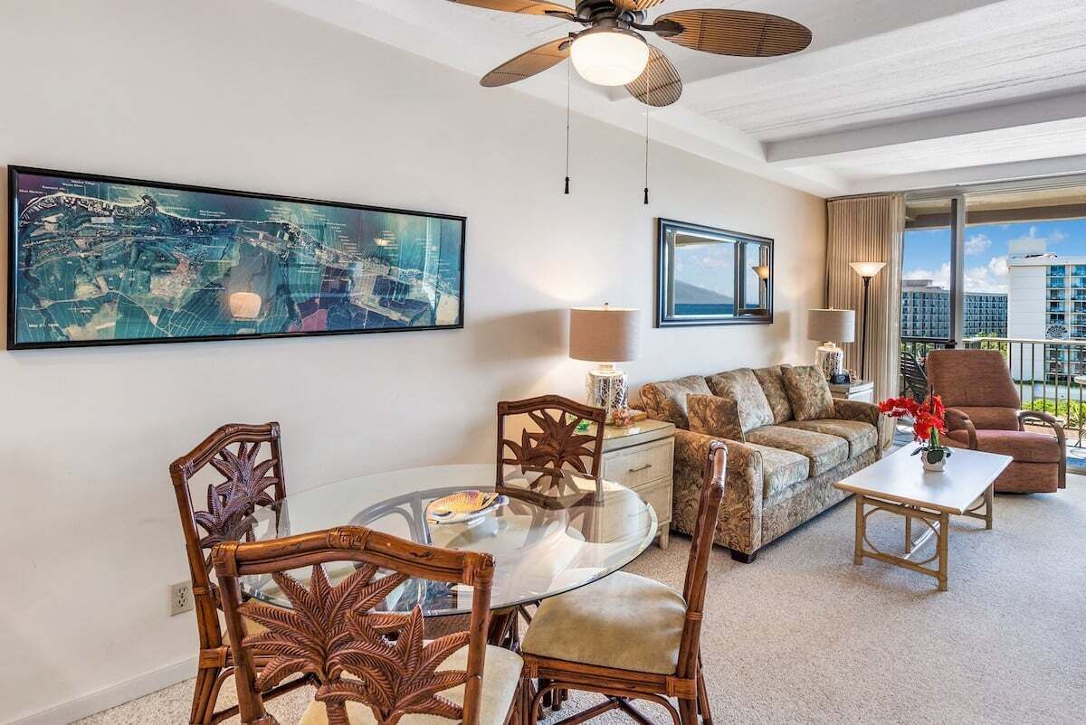 Ein Hotelzimmer mit Esstisch, Stühlen, einer Couch, einem Couchtisch, einem Deckenventilator und einem großen Stadtbild an der Wand.