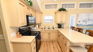 A kitchen with wooden cabinets, a microwave, a stove, a sink, and a dining area with chairs.