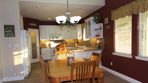 A kitchen with white cabinets, a wooden dining table, and a chandelier. - Home in park like setting with 3 acre lake . (La Grange)