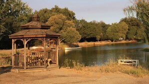 A gazebo by a calm lake with trees and a small dock. - Home in park like setting with 3 acre lake . (La Grange)