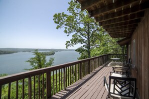 A wooden deck with a railing overlooking a lake, surrounded by trees. - Log Cabin-Panoramic Lakeview, Pool Table, Kids Bunks, Rustic Hangout & Fire Pit! (Rogers)