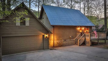 Une maison à deux étages avec un garage, une véranda et un drapeau américain.