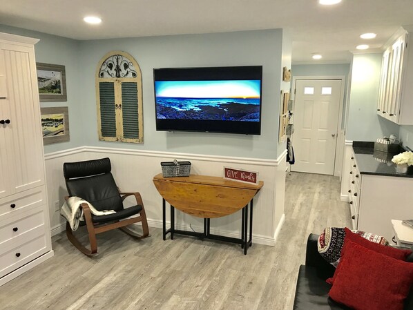 A living room with a TV, a rocking chair, a small table, and a 'GIVE Thanks' sign. - Charming, cozy, tranquil 1st floor condo -  5 minutes to Perkins Cove (Cape Neddick)